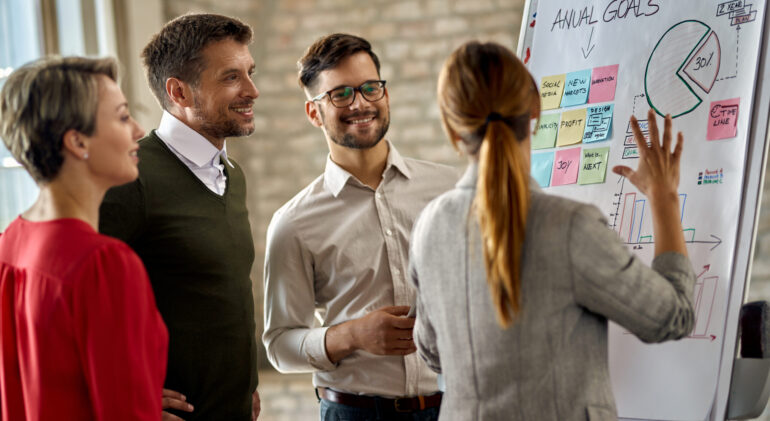 Team of happy entrepreneurs developing new business strategy on Happy business team cooperating while analyzing their business progress on whiteboard in the office.