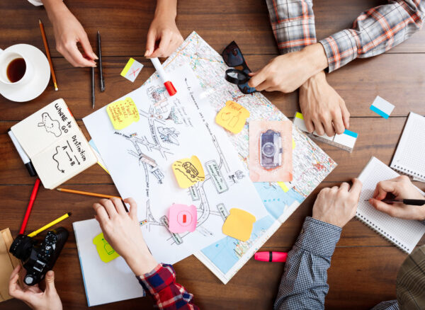 Picture of businessmen's hands on wooden table with documents, coffee and drafts