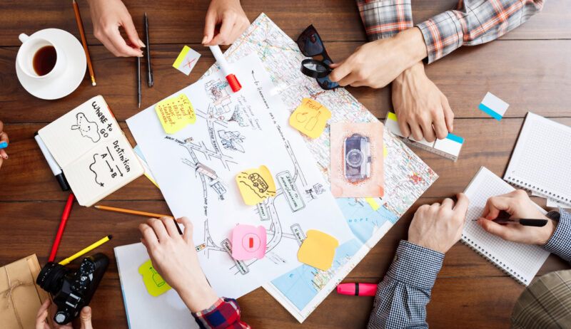 Picture of businessmen's hands on wooden table with documents, coffee and drafts