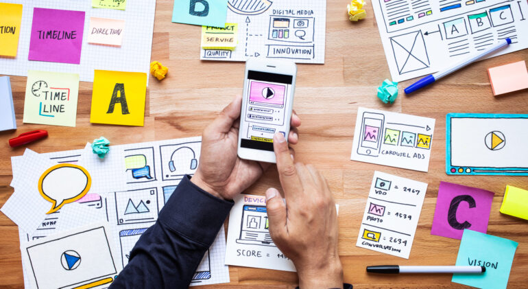 Business digital marketing with paperwork sketch and male hand touching smartphone on wood table.analysis strategy concepts ideas