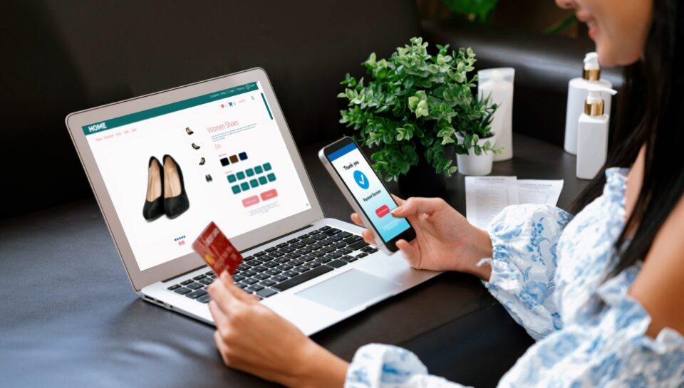 Young woman order or purchase product on internet using laptop. Blithe Young woman order or purchase product on internet using laptop and make transaction payment by smartphone. Online shopping lifestyle with credit card via internet banking on mobile application. Blithe